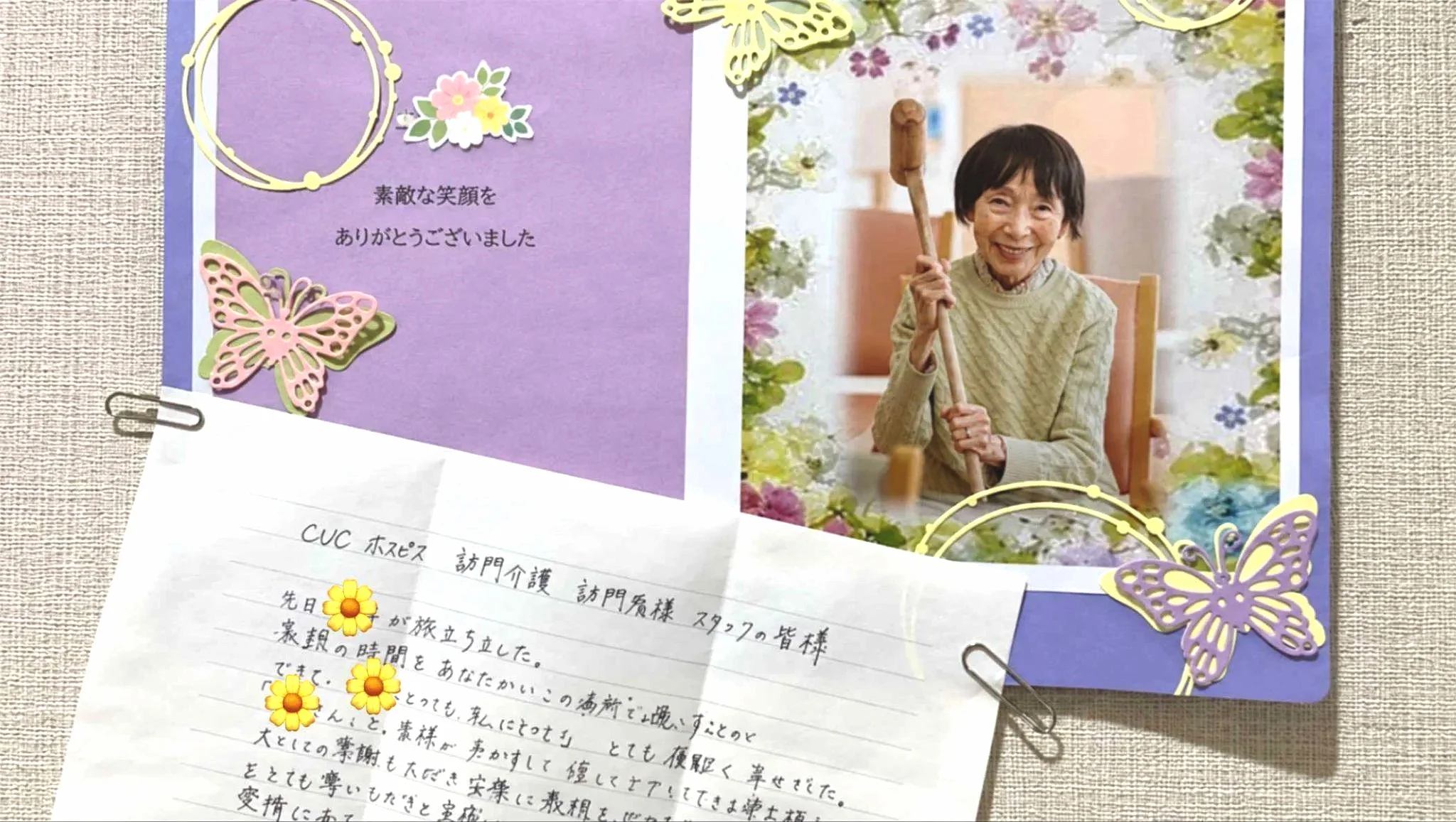 ReHOPE 星ヶ丘のご家族から届いた手書きのお手紙と、笑顔のご入居者さまの写真。紫色の台紙に花や蝶の飾りが添えられ、壁に掲示されている