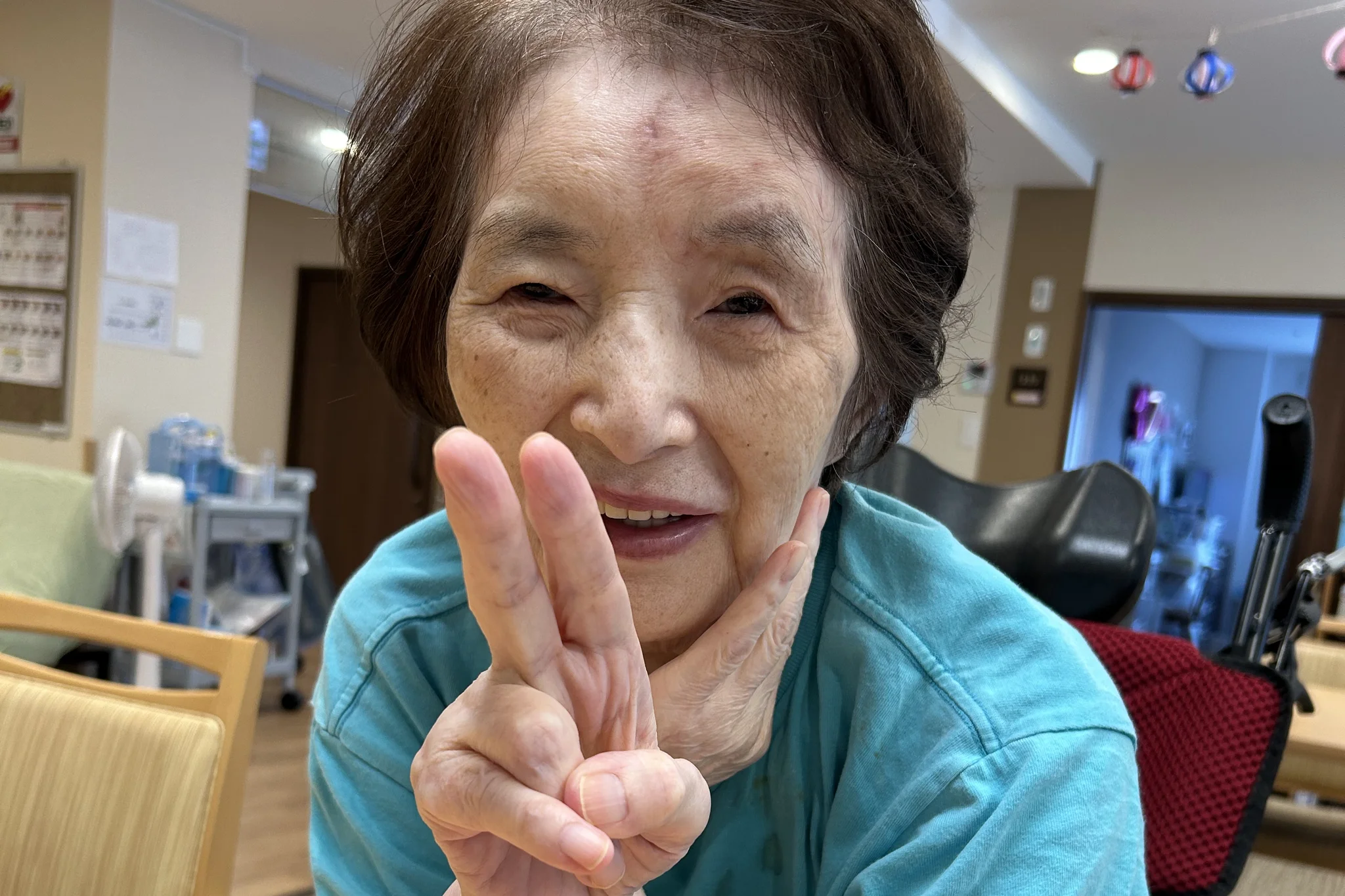 ReHOPE 鷺沼の居室で、カメラに向かってピースサインをする笑顔のご入居者さま