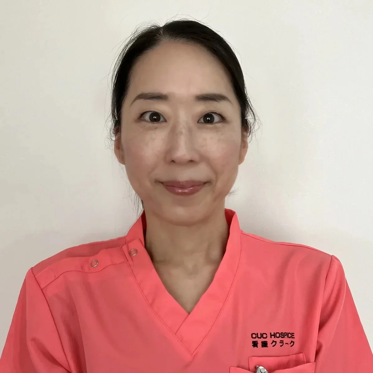 赤羽朝香さんの顔写真。コーラルピンクのユニフォームを着て正面を向いている