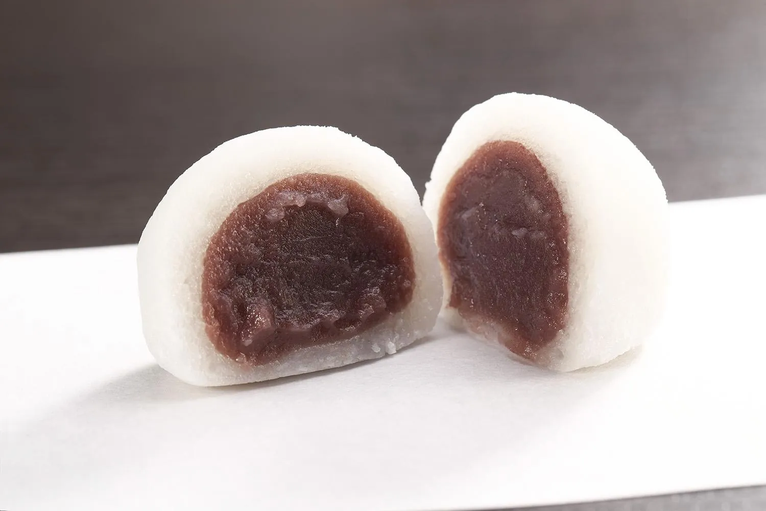 半分に切ったおかゆ大福。白くやわらかな生地の中に、なめらかなこしあんが包まれている